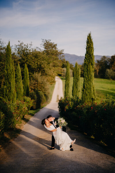 Bride and groom embracing on a cypress-lined road at Tenuta di Rota in Tuscany, captured by a Tuscany wedding photographer at sunset.
