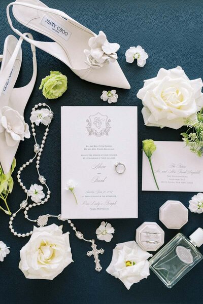 Detail shot of wedding invitation suite, bridal shoes and rings styled with white roses, fine art wedding photography
