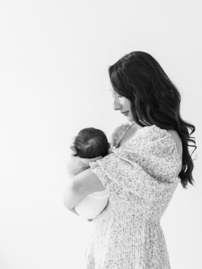 Black and white photo of a mom holding her newborn in a photography studio in Seattle, WA