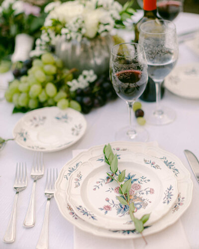 A photo of a table setting for a wedding reception with floral in the background.