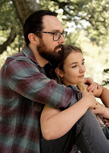 engaged couple holding onto each other sitting and looking at a view
