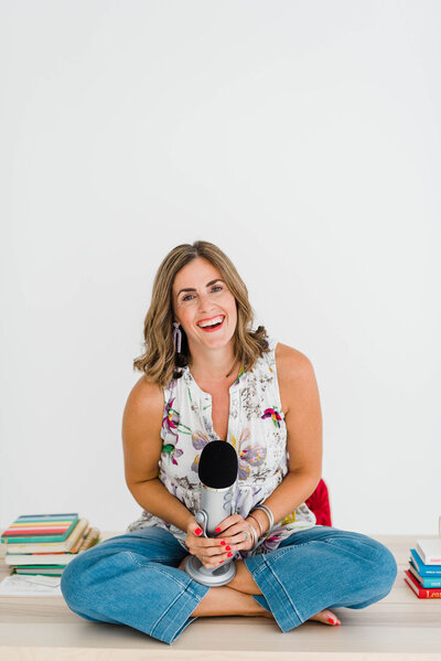 woman sitting on a table holding a podcast mic in her lap