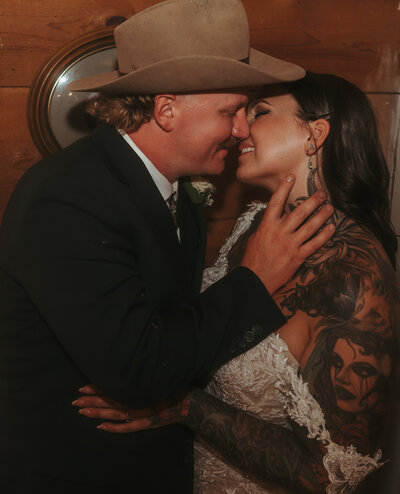 western couple kissing, Bride with tattoos and groom with cowboy hat