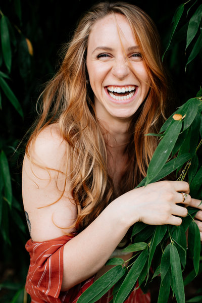 woman smiling while standing in leaves