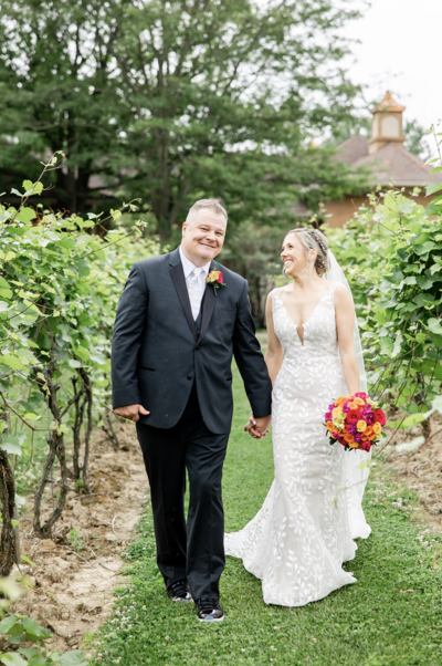 Bride and Groom walking through vineyard  on their wedding day at Gervasi Vineyard photographed by akron ohio wedding photographer
