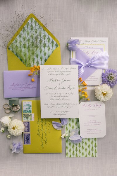a stationery suite with a purple, green, and yellow color scheme and whimsical design details