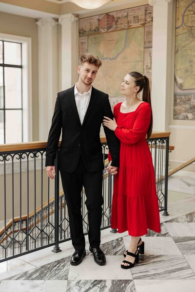 man and woman standing next to stair railing while gently smiling