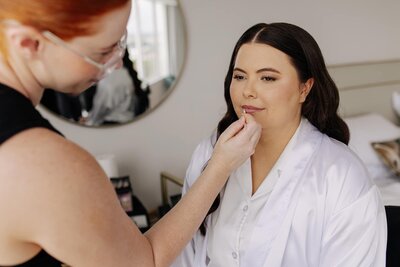 soft glam makeup and waves, pink lips being applied