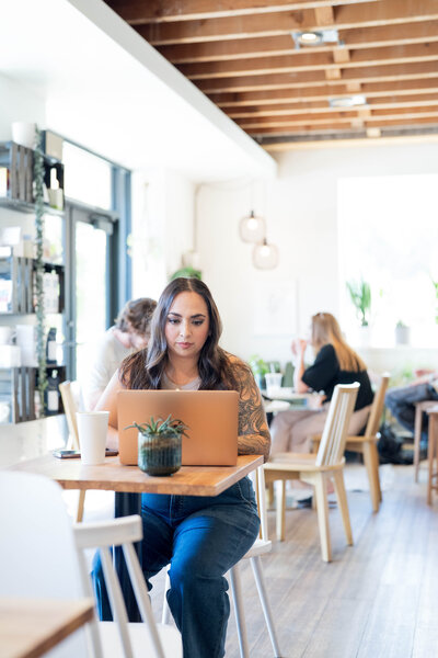 Stephanie, Founder of BCWise Consulting, sitting at a coffee shop on her laptop 