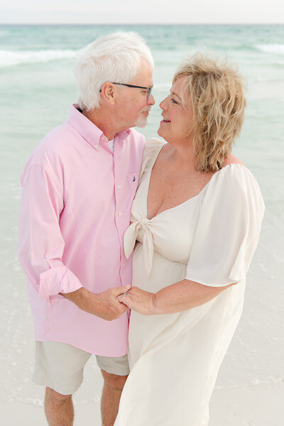 Sweet moment between grandparents holding hands during a soft pastel beach session in Destin, FL by Andrea Krey Photography