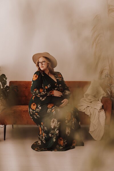 Pregnant mother sitting on couch in a floral dress