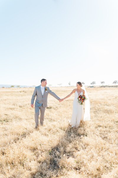 wedding portrait where bride and groom are walking through a field at a private estate property in eastern washington 