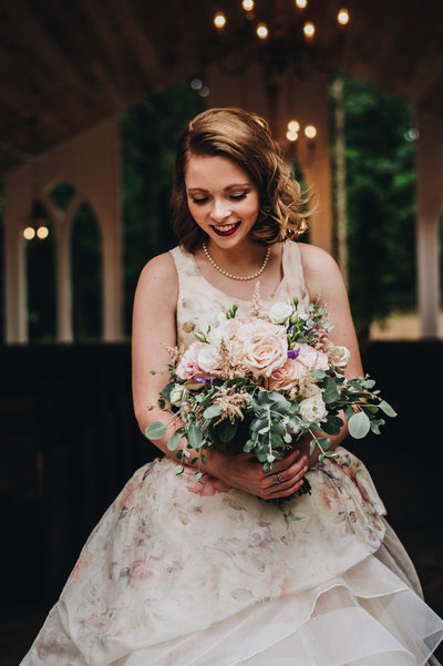 A vintage bride smiles at her pink bouquet