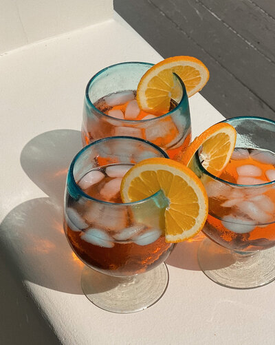 Three glasses of iced drinks with orange slices