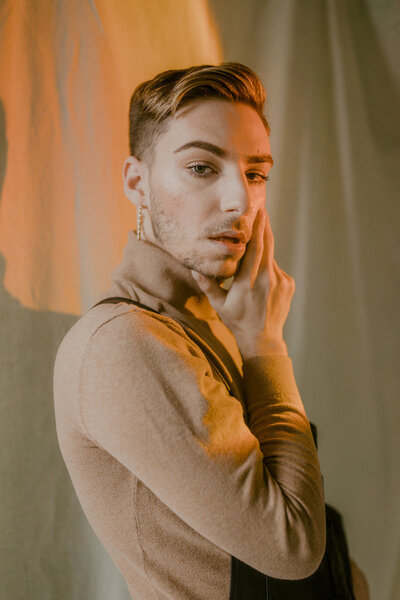 An artful portrait featuring warm, moody lighting and elegant posing, capturing a striking expression of confidence and self-expression.
