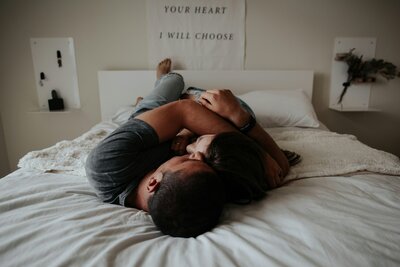 Couple lying together on a bed, representing intimacy and emotional connection in couples coaching