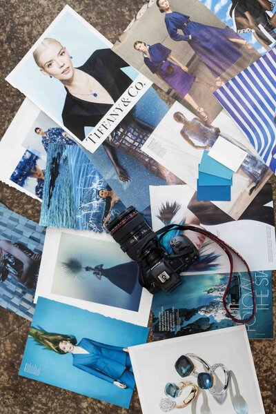 Creative brand mood board featuring ocean-inspired photography, blue color swatches, and professional camera equipment laid out for visual storytelling