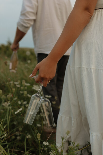 couple walking to beach with champagne glasses for lifestyle photos in pei