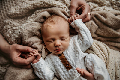 Newborn snuggling in tan blanket with eyes open