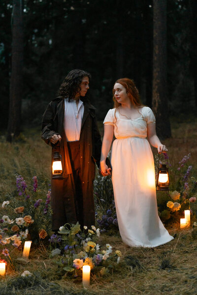 A couple holding hands and lanterns surrounded by candles and flowers