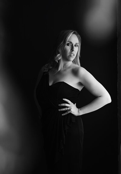 portrait of woman standing with elbow bent, looking at camera