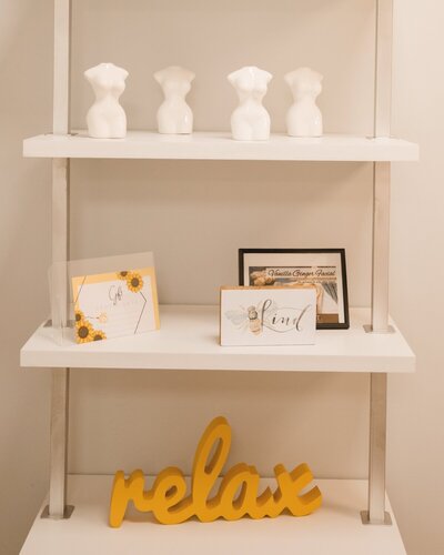 Decorative product shelf with 'Relax' sign inside Artista Beauty Studios salon suite in Bethel, CT.