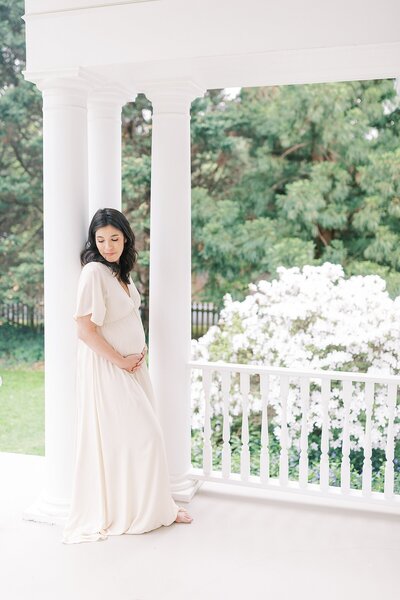 Pregnant woman leaning against a white column during Washington DC maternity session