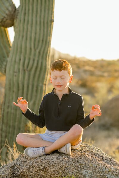 little boy on a rock in the desert being zen 