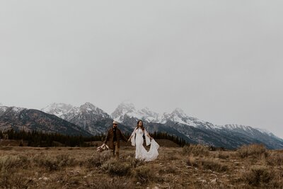 woman standing in front of mountains and holding her hair