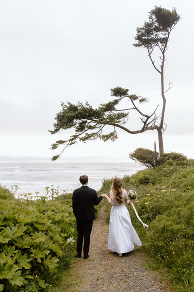 Couple walking toward a beach on the Oregon Coast during their elopement.