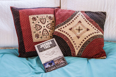 Location Branding photo red patterned pillows on blue bed spread with Joshua Tree brochure