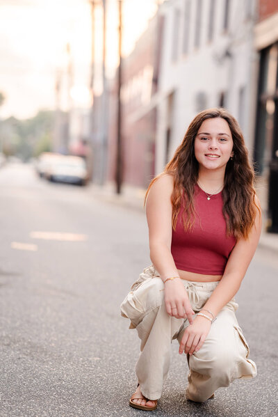A high school senior poses on an old street during her senior casual with Justine Renee Photography.
