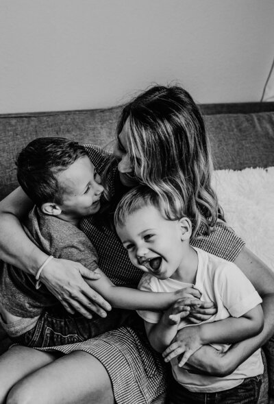 A mother and her two boys relax on a couch, sharing a moment of togetherness and joy.