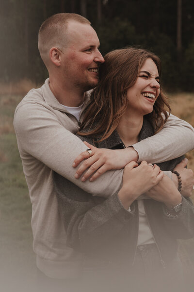 Een man en vrouw omarmen elkaar voor een witte achtergrond, stralend van liefde en verbondenheid.