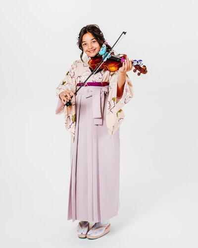Girl in modern hakama kimono playing violin to celebrate graduation (卒業式).