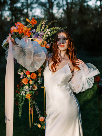 bride with colorful bouquet blocking sun on her face