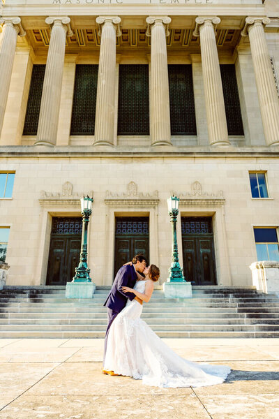 Bride and Groom dip kissing in front of the Dayton Masonic Temple in Dayton, OH Captured by wedding photographer Rogue State Photography.