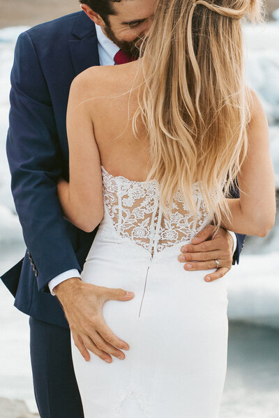 groom grabs his brides booty after reciting their vows at the Jokulsarlon Iceberg Lagoon during their destination elopement in Iceland