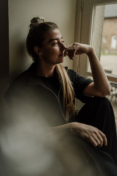Stijlvol lifestyleportret van een vrouw die bij een raam zit, gefotografeerd door Beau à Bo - persoonlijke en natuurlijke fotografie met aandacht voor emotie