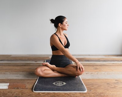 a woman sits in lotus pose turned to the left wearing a black workout outfit