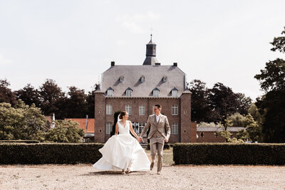 Bruiloft kasteel aldenghoor op achtergrond bruidspaar bruid en bruidegom rennen naar de camera en kijken naar elkaar