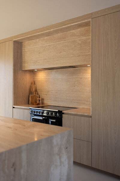 Detail van een maatwerkkeuken met houten elementen, natuursteen en geïntegreerde apparatuur.
