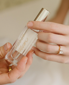 bride's hand holding a jo malone fragrance engraved with "mom" in gold lettering