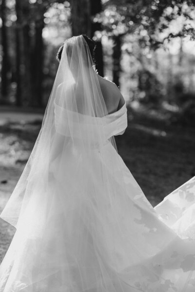 Bride walks away with veil and dress shimmering in sunlight