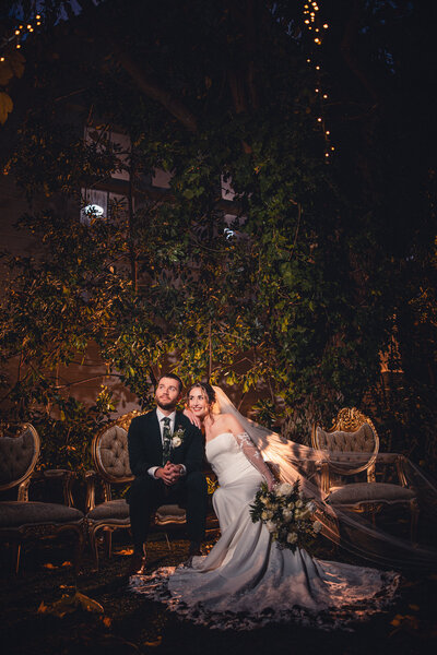 Bride and groom embracing each other under a twinkle-light-lit garden archway at Green Gables Wedding Estate wedding venue in San Marcos.