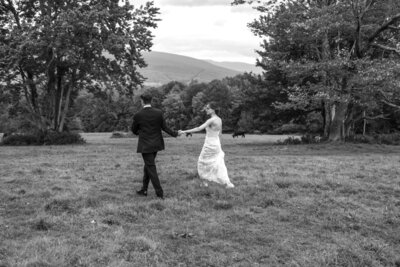 B & W photo of bridge and groom walking together holding hands, Buxton School wedding