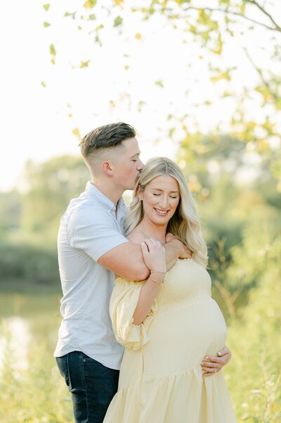 Husband kisses his wife's forehead at Milwaukee maternity photoshoot