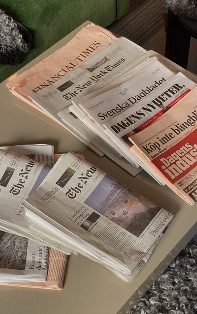 stack of newspapers from around the world on a coffee table