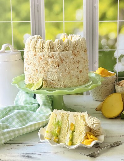 a mango cake decorated with white frosting and toasted coconuts