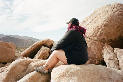 A person sitting on a rock looking off into the distance.